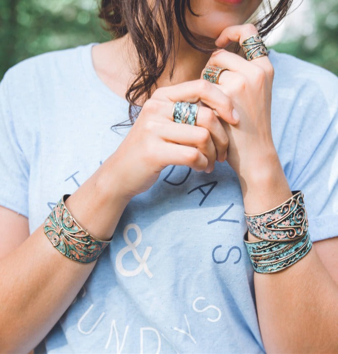 Woman wearing handmade adjustable ring made of brass and copper with a vintage turquoise patina finish.