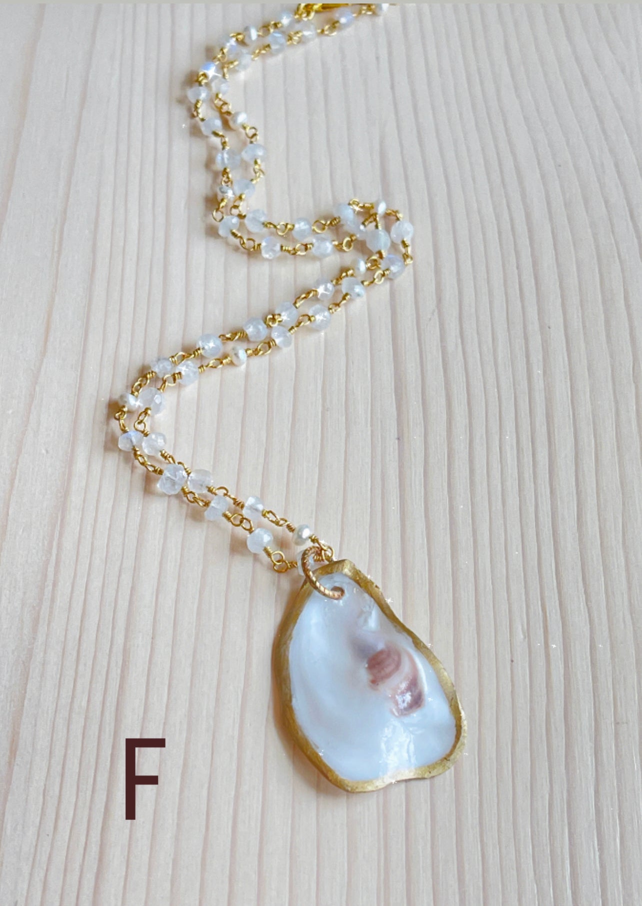 F.  Oyster shell with rainbow moonstone beaded chain.