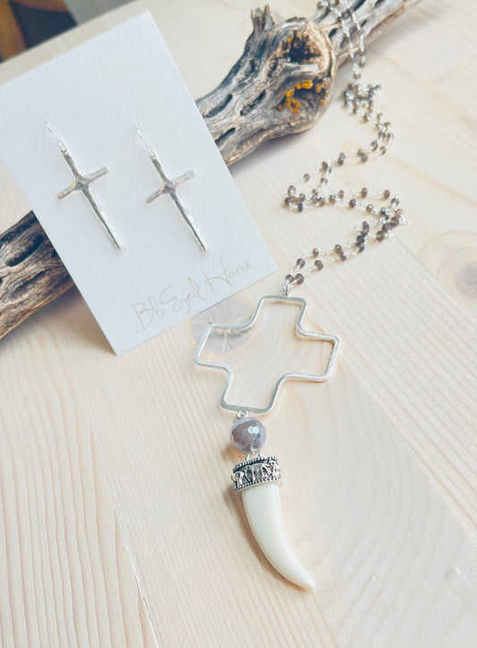 Carmen Necklace with cross earrings displayed on top of driftwood