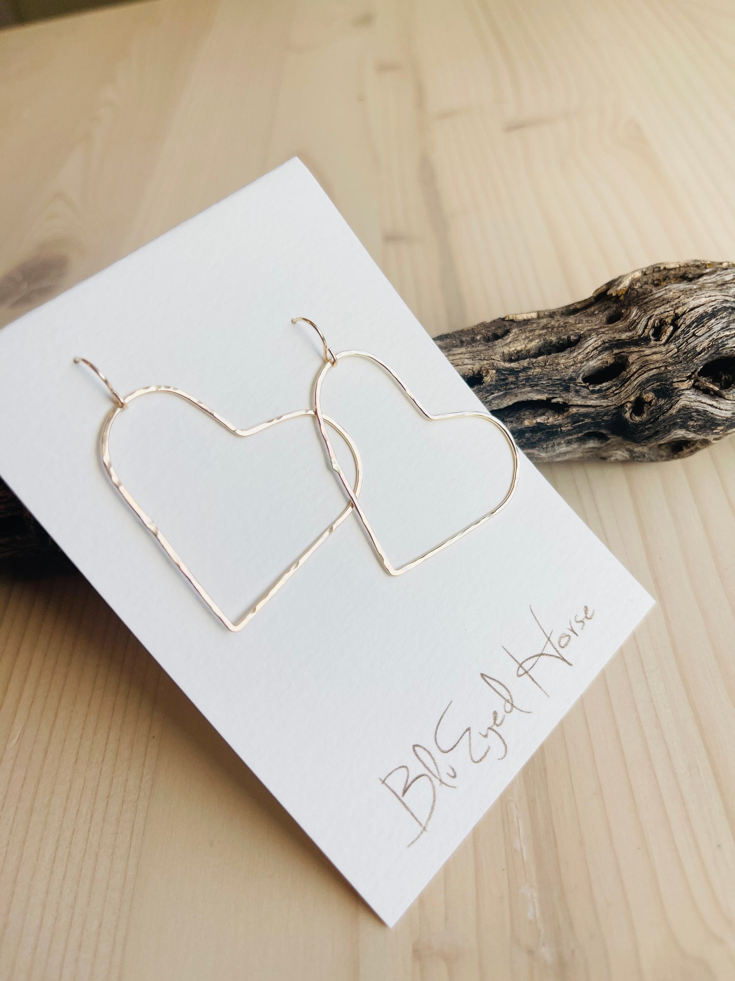 Gold Heart Earrings displayed on driftwood