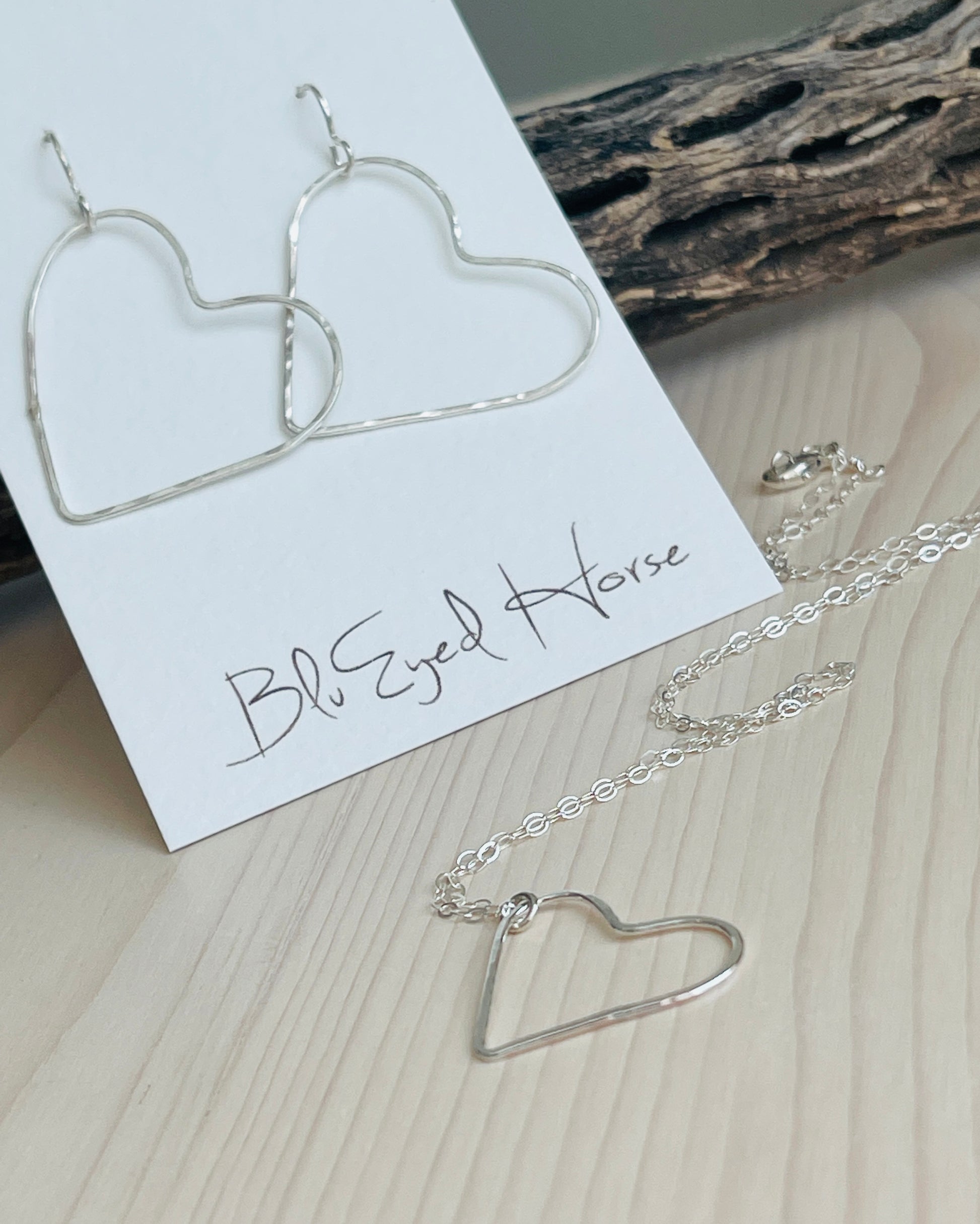 Silver Floating Heart Necklace with heart shaped earrings with driftwood in background