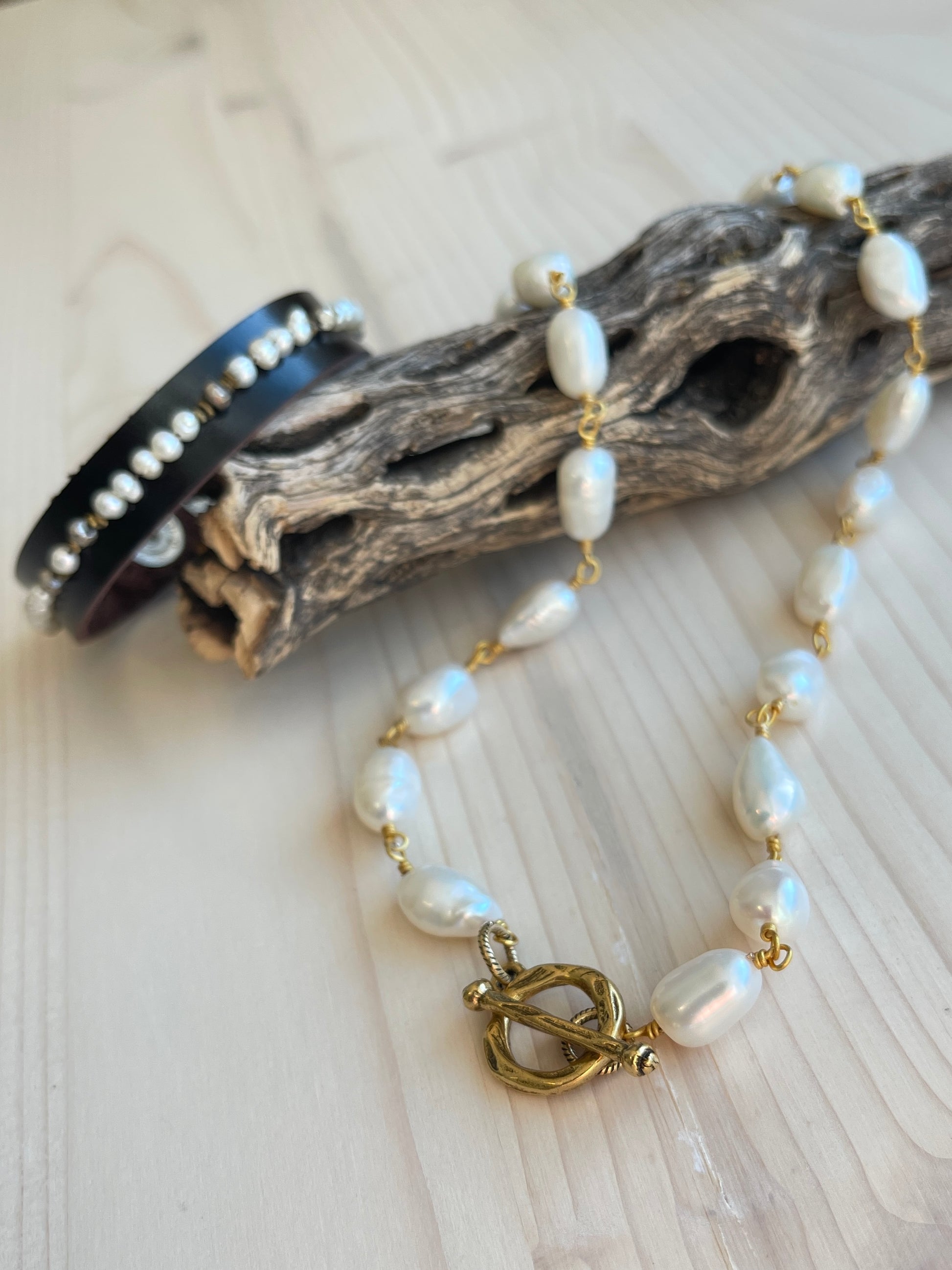 Blair Bracelet displayed on driftwood with pearl choker