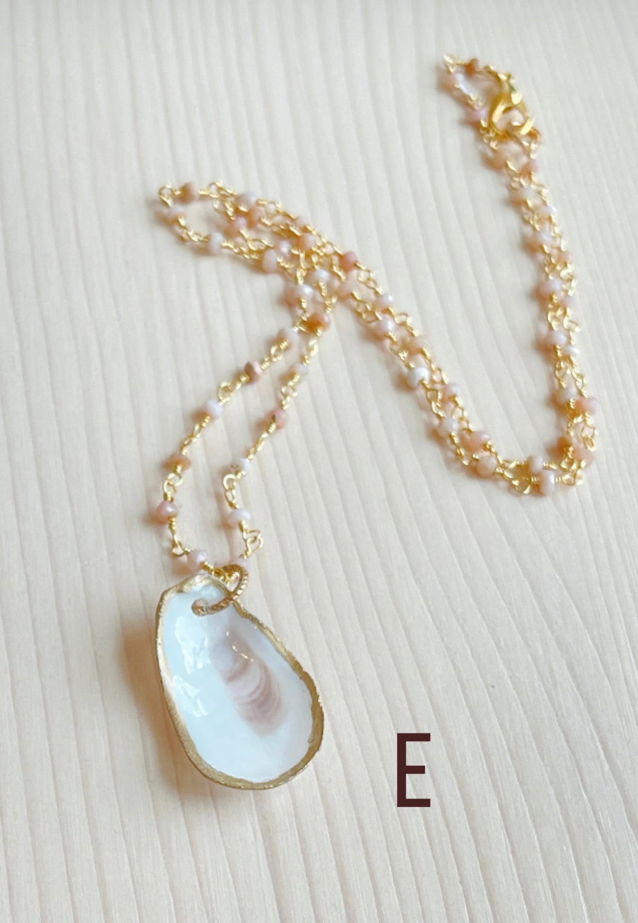 E.  Oyster shell with pink Opal gemstone beaded chain.