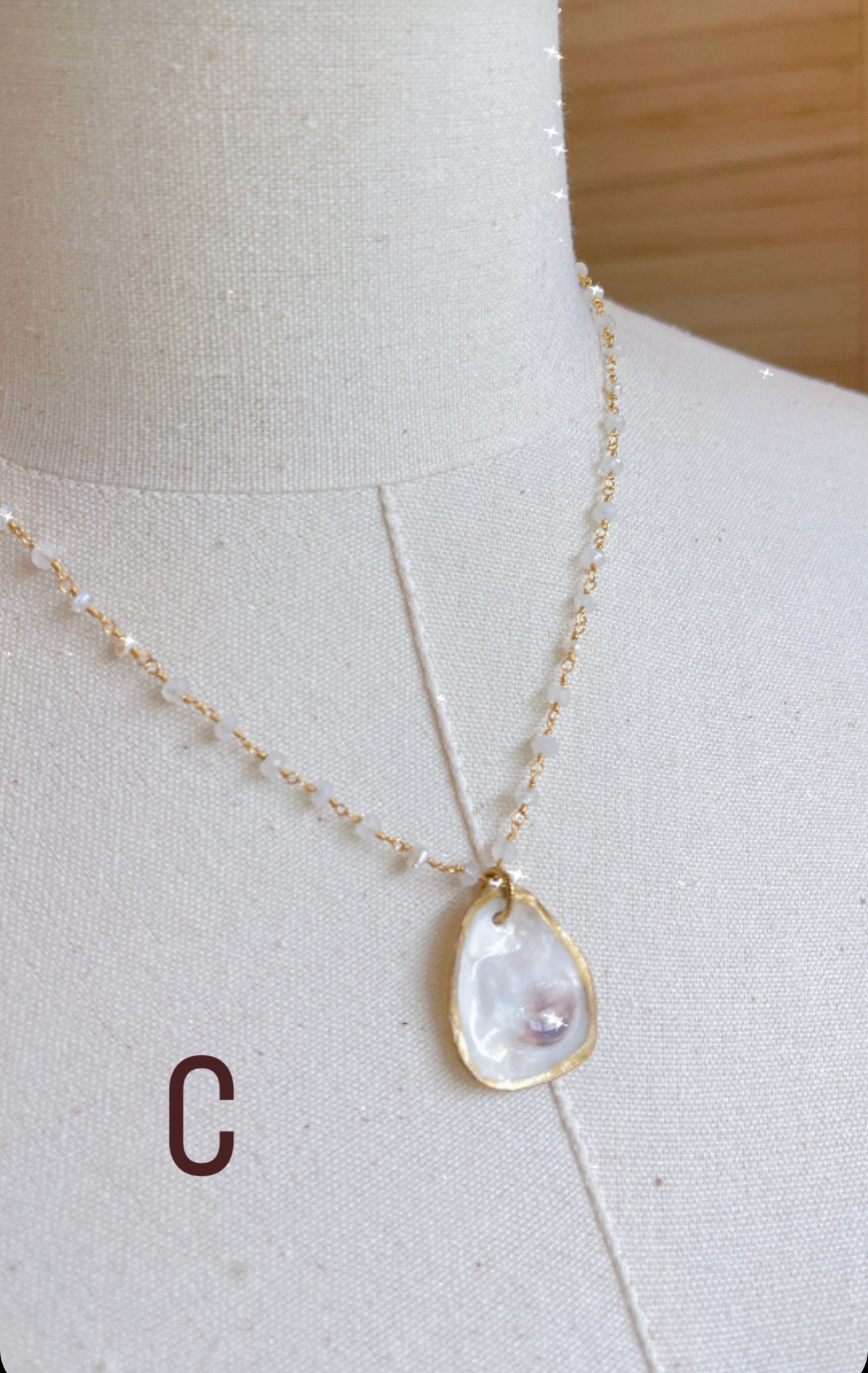 C.  Oyster shell with rainbow moonstone beaded chain.